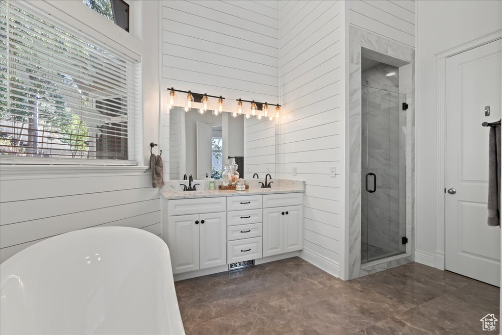 Full bathroom featuring wood walls, a shower stall, double vanity, and a freestanding tub