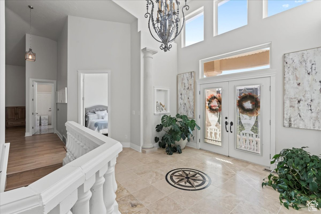 Entrance foyer with a high ceiling, french doors, a chandelier, and baseboards
