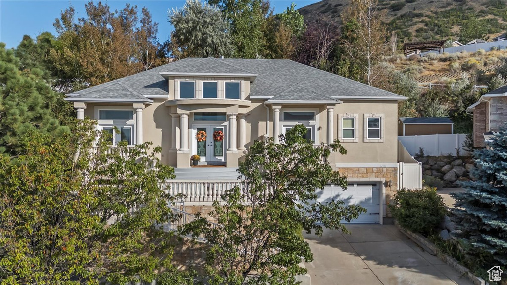 View of front of property featuring stucco siding, concrete driveway, an attached garage, stone siding, and a shingled roof