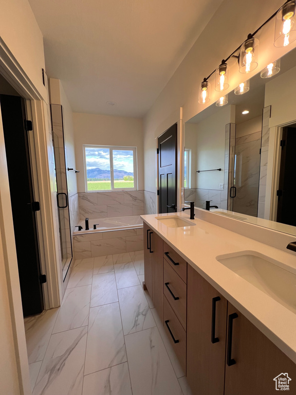 Full bath with marble look tile flooring, a bath, a stall shower, and double vanity