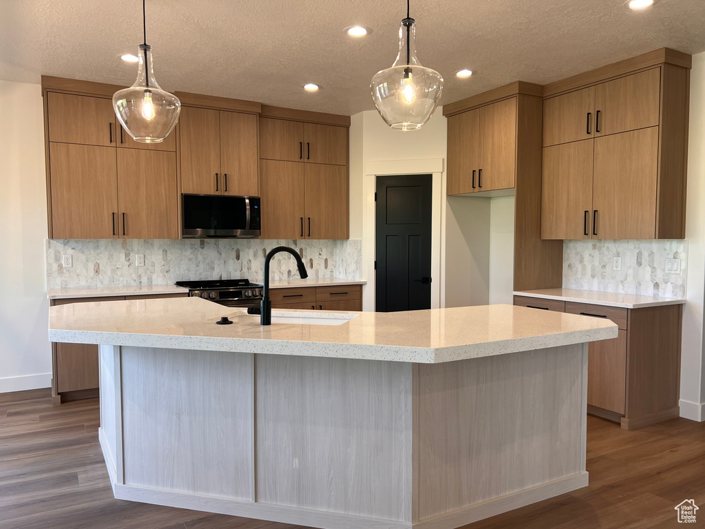 Kitchen with stainless steel microwave, tasteful backsplash, dark wood-type flooring, recessed lighting, and a textured ceiling