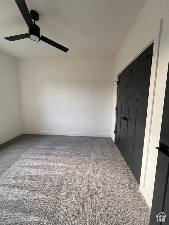 Carpeted spare room with a ceiling fan and baseboards