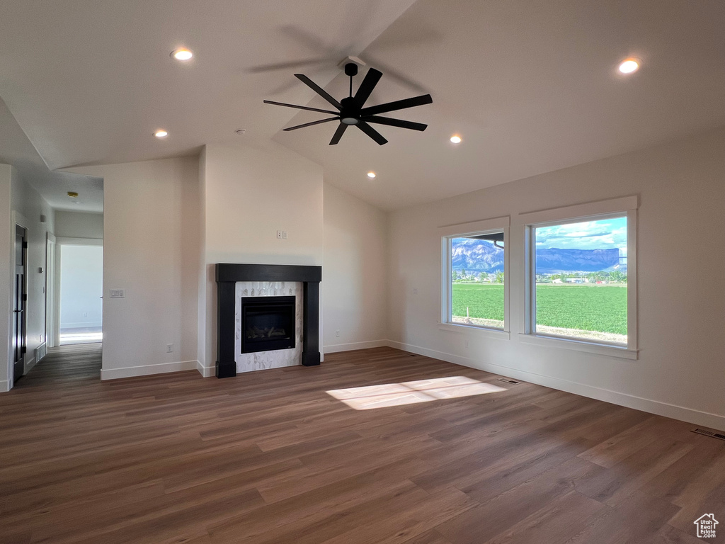 Unfurnished living room featuring a fireplace, baseboards, wood finished floors, vaulted ceiling, and recessed lighting