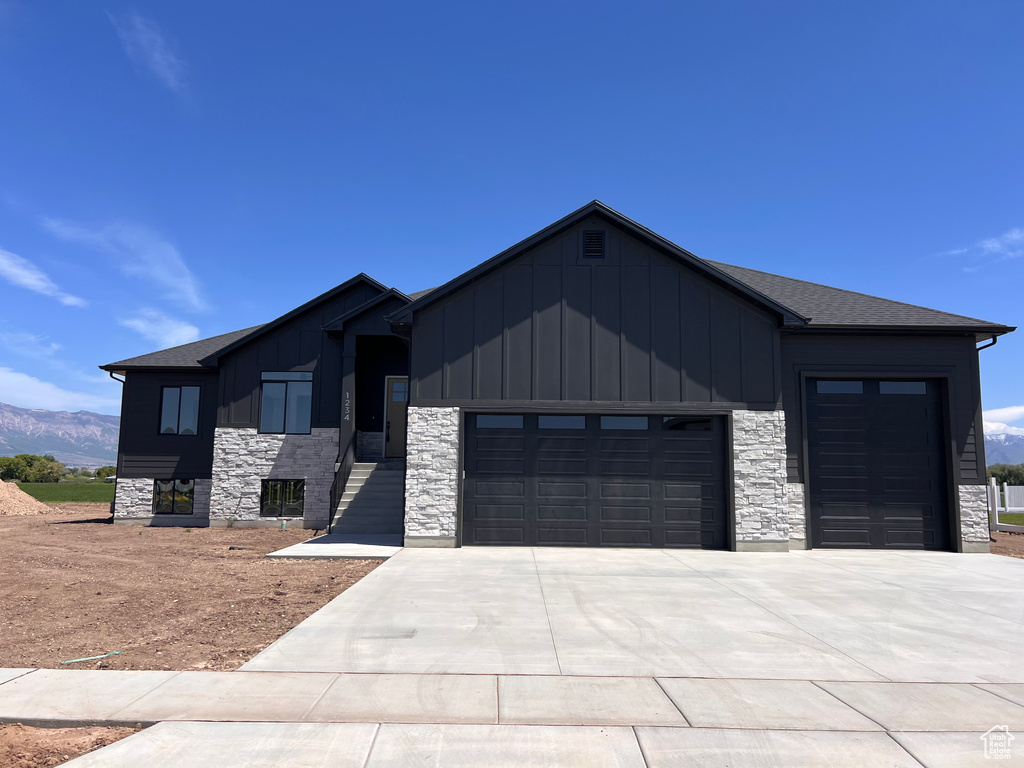 View of front of home featuring board and batten siding, a garage, stone siding, and concrete driveway