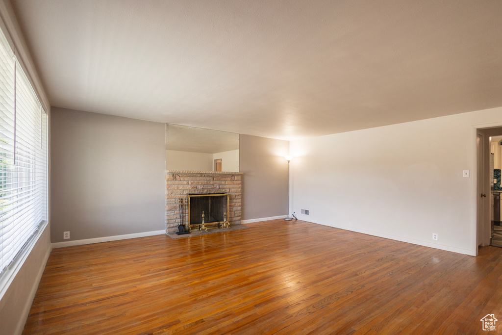 Unfurnished living room featuring wood finished floors, a fireplace, and baseboards
