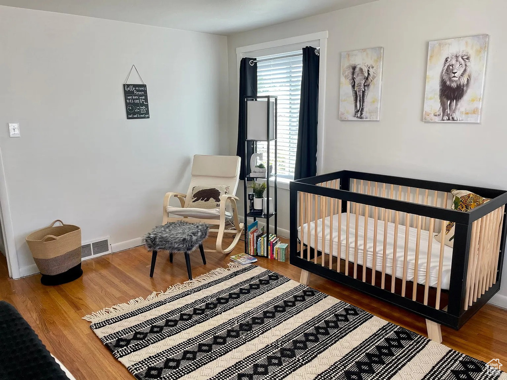 Bedroom featuring wood finished floors, baseboards, and a crib