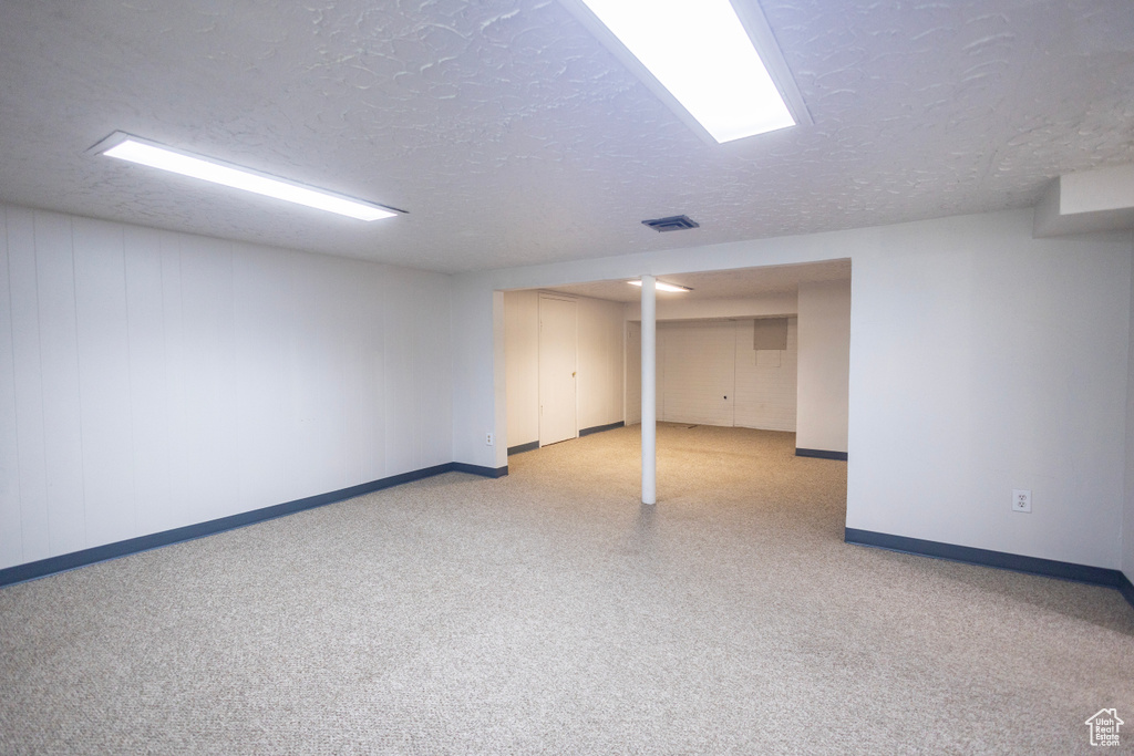 Finished below grade area featuring baseboards and a textured ceiling