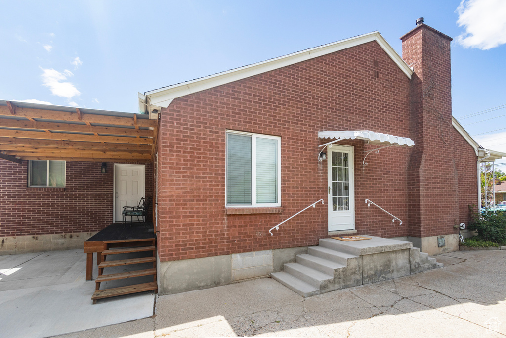 View of front of house featuring crawl space, brick siding, and a chimney