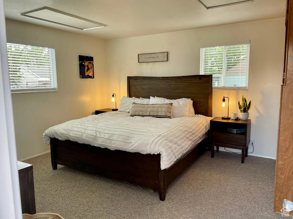 Bedroom featuring carpet flooring, attic access, and multiple windows