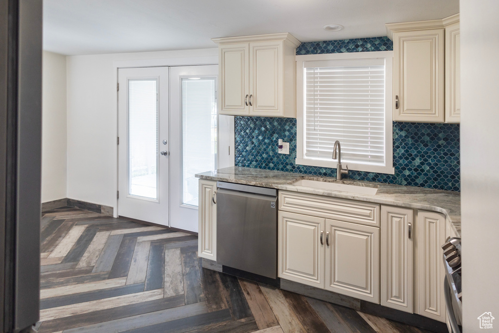 Kitchen featuring stainless steel dishwasher, cream cabinets, a sink, french doors, and decorative backsplash