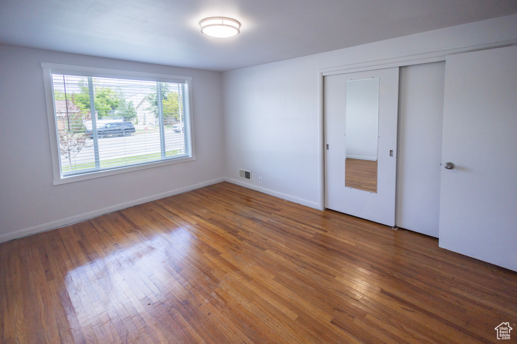 Unfurnished bedroom with wood finished floors, baseboards, and a closet