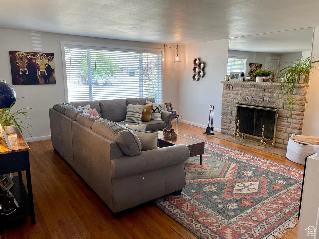 Living room with baseboards, wood finished floors, and a stone fireplace