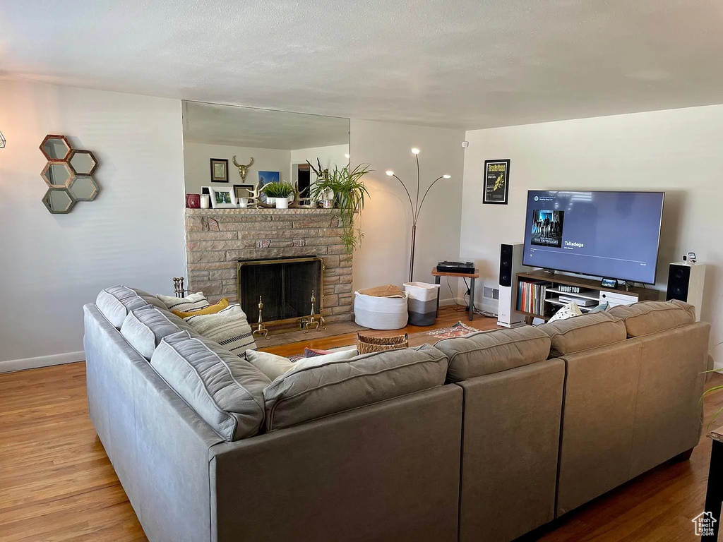 Living room featuring wood finished floors, baseboards, and a brick fireplace