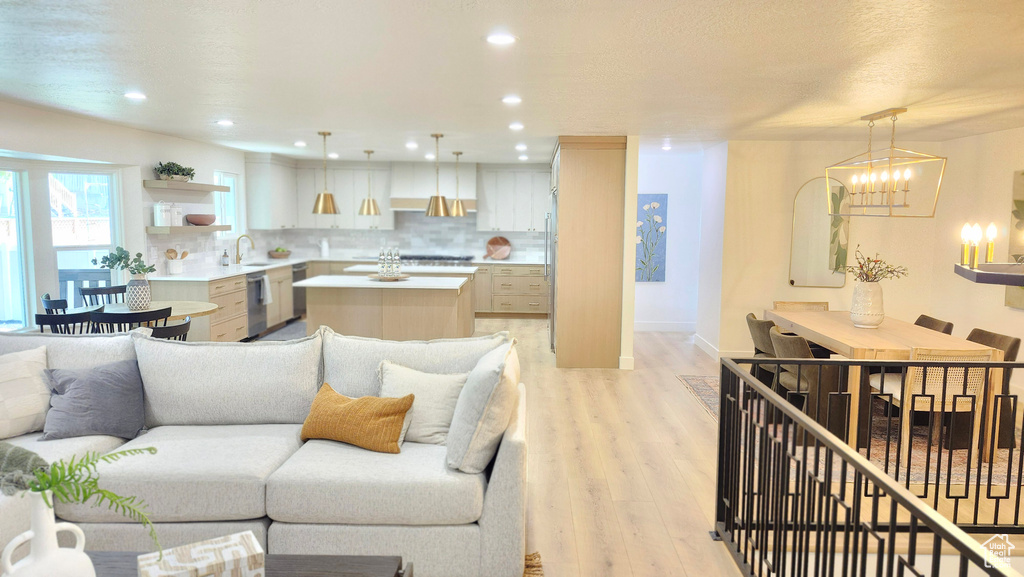 Living room with light wood-type flooring, a chandelier, baseboards, and recessed lighting