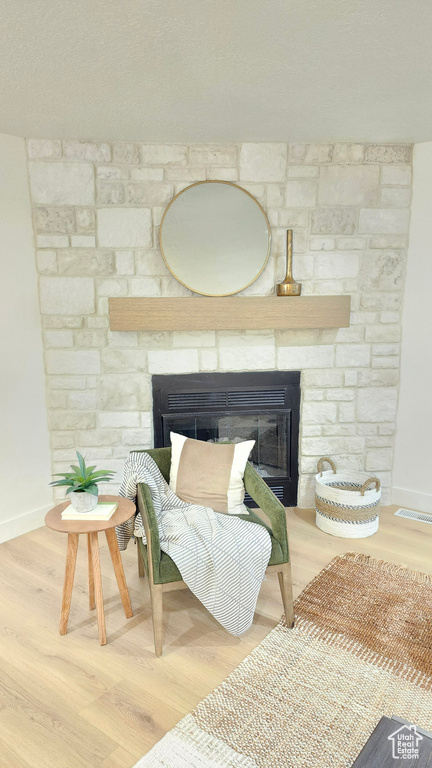 Detailed view of a stone fireplace, baseboards, and wood finished floors