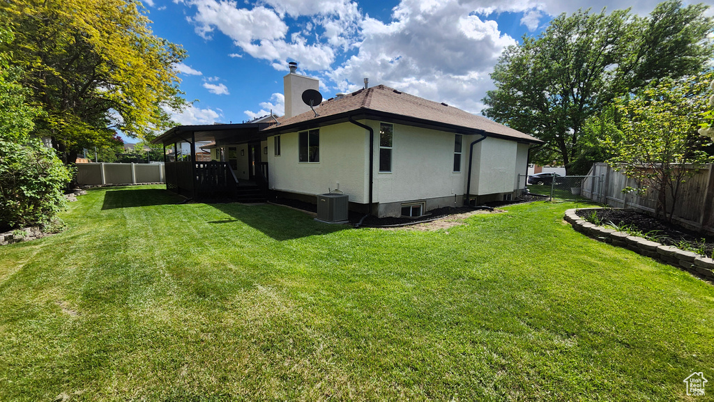 Back of house with a chimney, central AC, and stucco siding