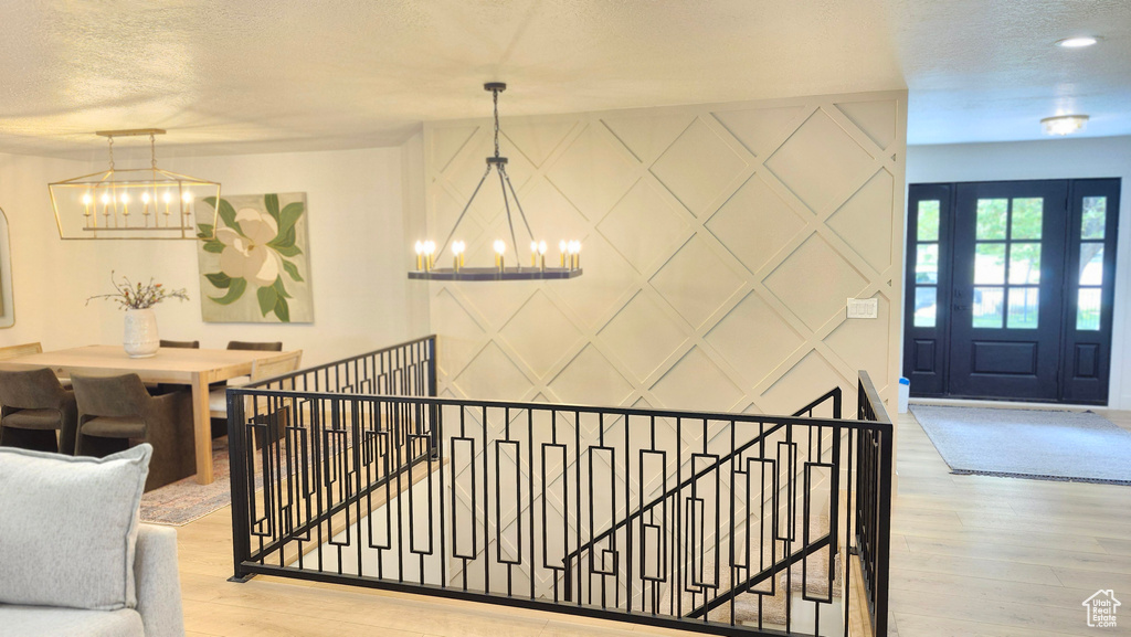Staircase featuring a chandelier, a decorative wall, wood finished floors, and a textured ceiling