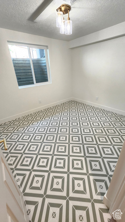 Empty room featuring a textured ceiling and baseboards