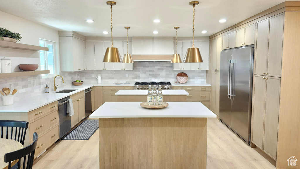 Kitchen featuring appliances with stainless steel finishes, a sink, a center island, light wood finished floors, and recessed lighting