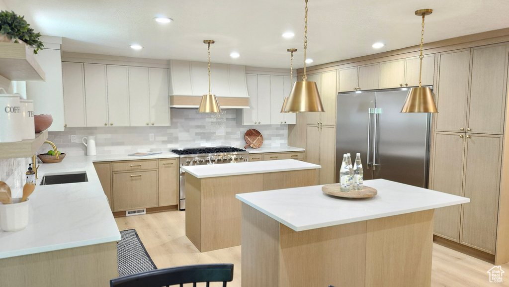 Kitchen featuring a kitchen island, high end appliances, light wood finished floors, tasteful backsplash, and recessed lighting