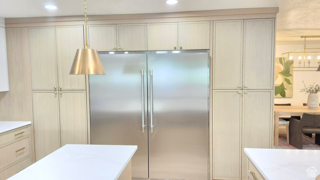 Kitchen with stainless steel built in refrigerator, light countertops, pendant lighting, and recessed lighting