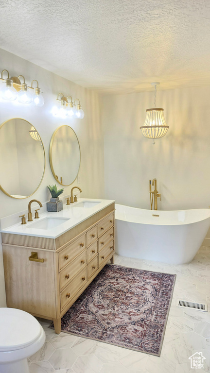Full bathroom with double vanity, a soaking tub, a textured ceiling, toilet, and marble look tiles