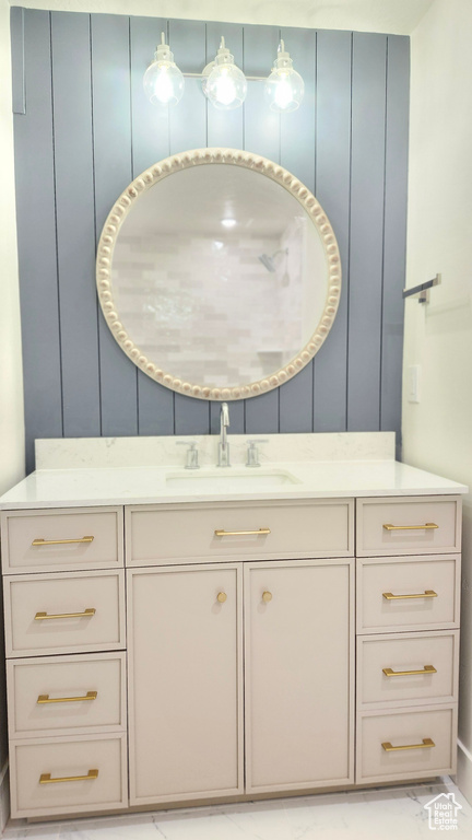 Bathroom featuring a decorative wall, marble look tile flooring, and vanity