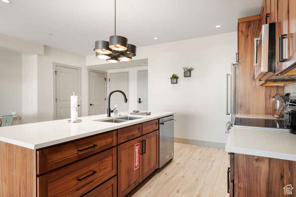 Kitchen with a sink, dishwasher, light countertops, a kitchen island with sink, and recessed lighting