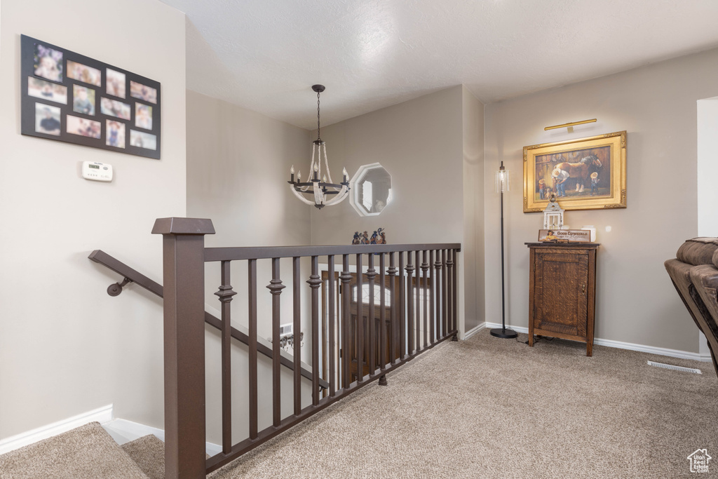 Staircase with a chandelier, carpet flooring, and baseboards