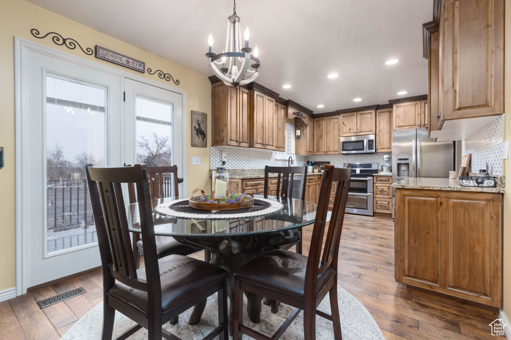 Dining room featuring plenty of natural light, a chandelier, light wood-style flooring, recessed lighting, and baseboards