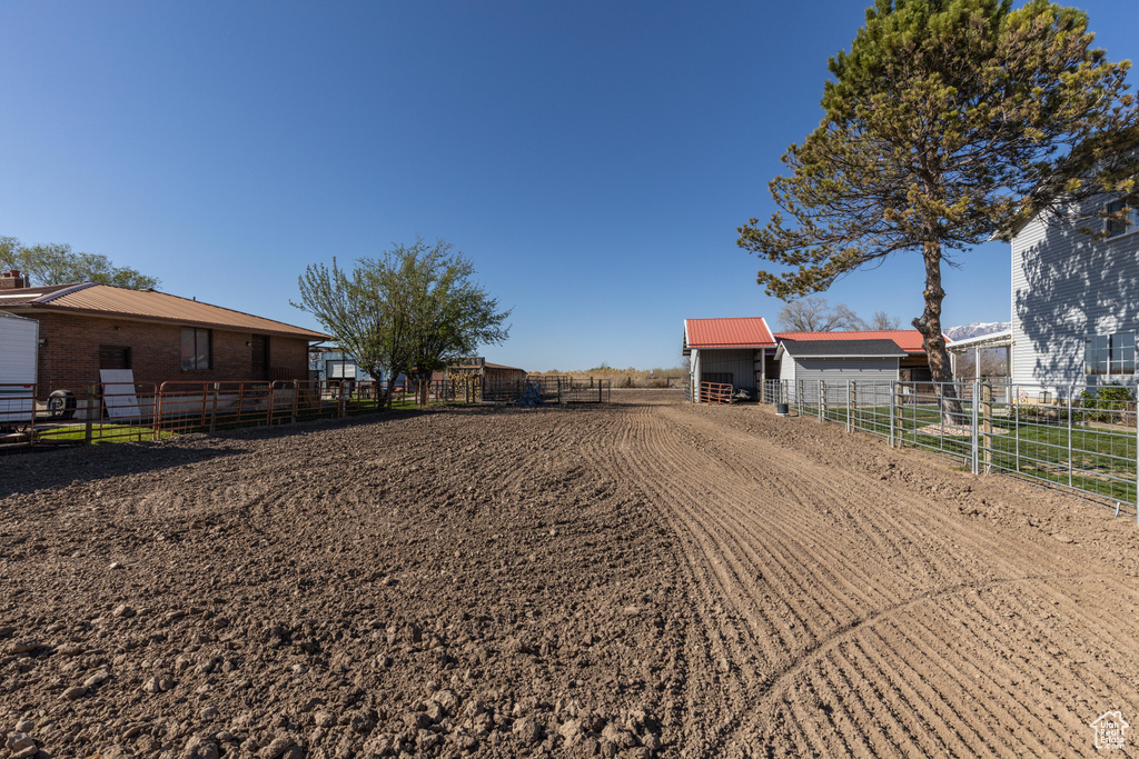 View of dirt / gravel driveway featuring an enclosed riding area and an exterior structure