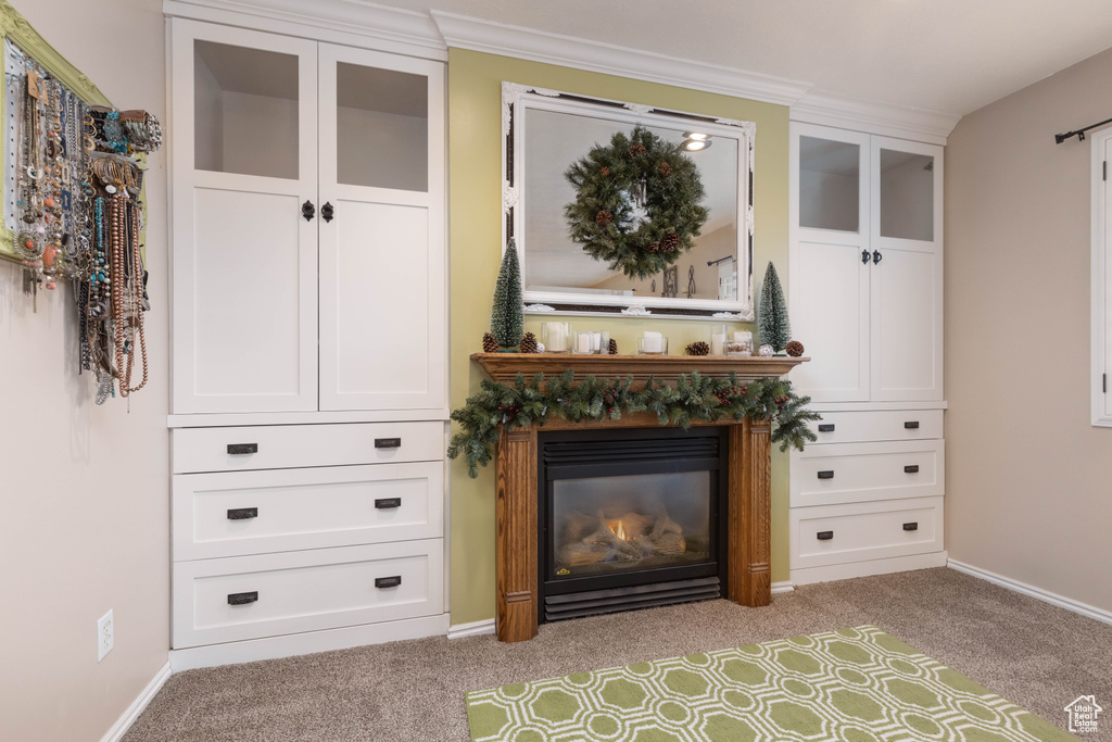 Detailed view of carpet floors, a glass covered fireplace, baseboards, and ornamental molding