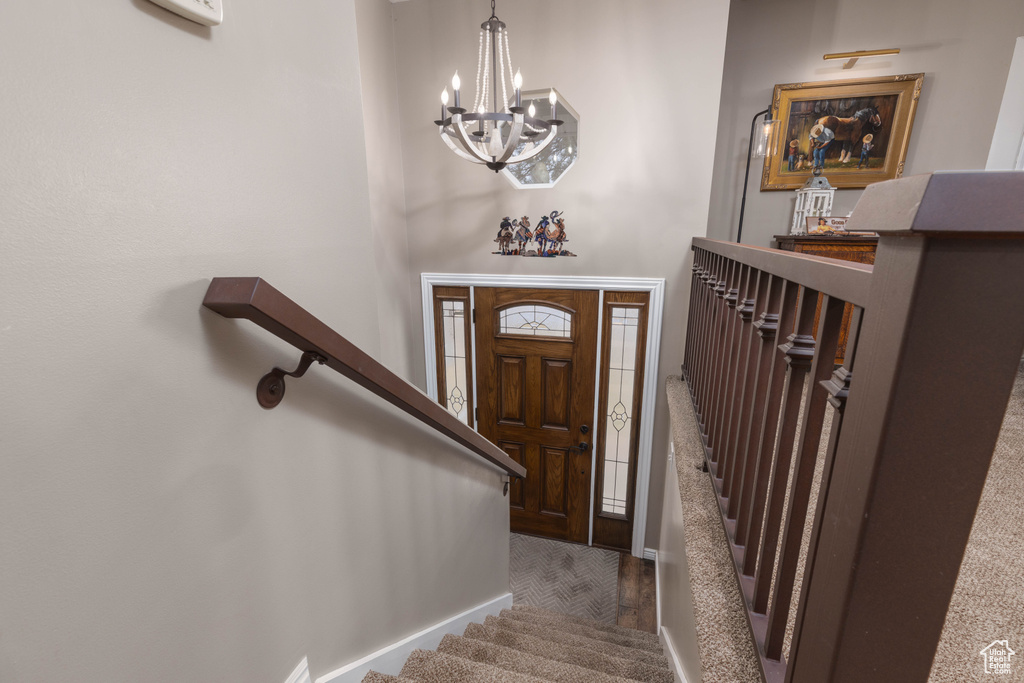 Foyer featuring a chandelier, stairway, wood finished floors, and baseboards