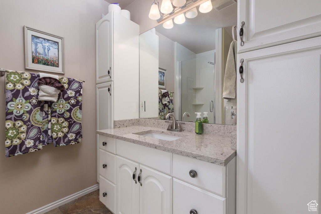 Full bathroom with vanity, baseboards, and a shower with shower door