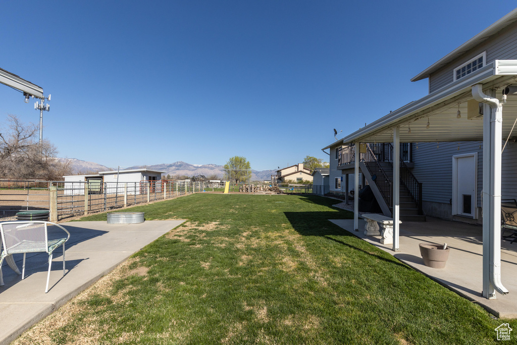 View of yard with stairs, a mountain view, and a patio area
