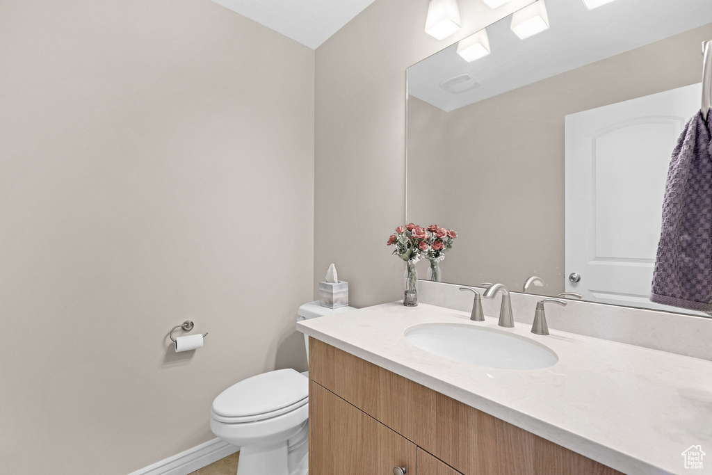 Half bath with vanity, toilet, and baseboards