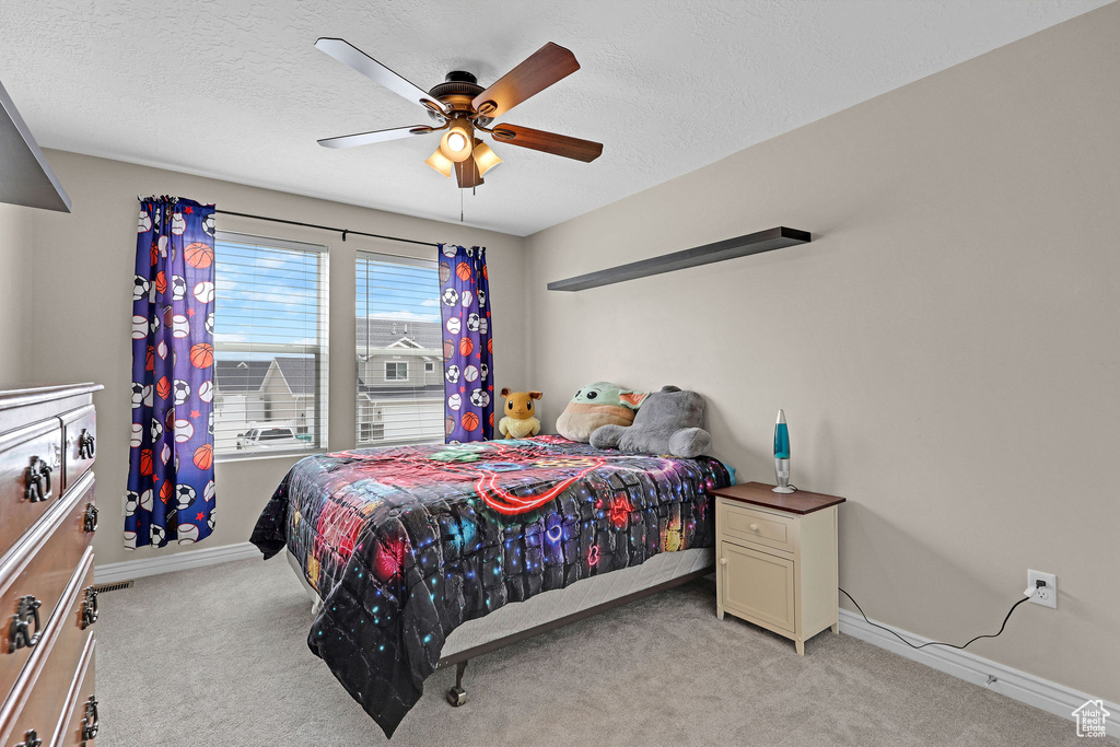 Bedroom with light carpet, baseboards, a textured ceiling, and ceiling fan
