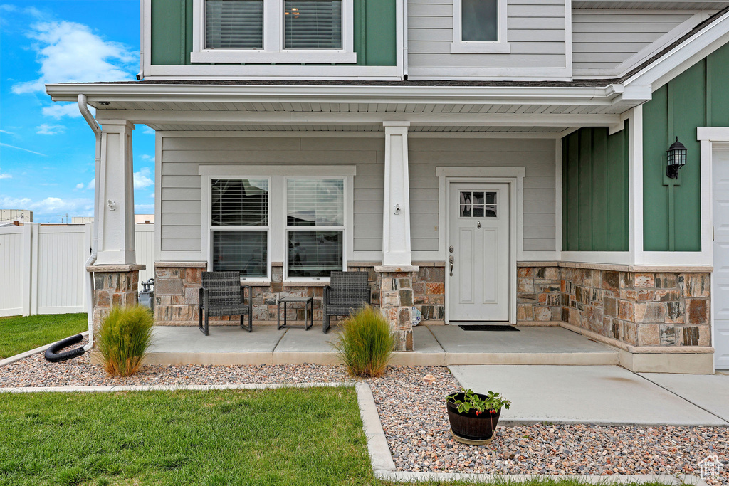 View of exterior entry with stone siding and a porch