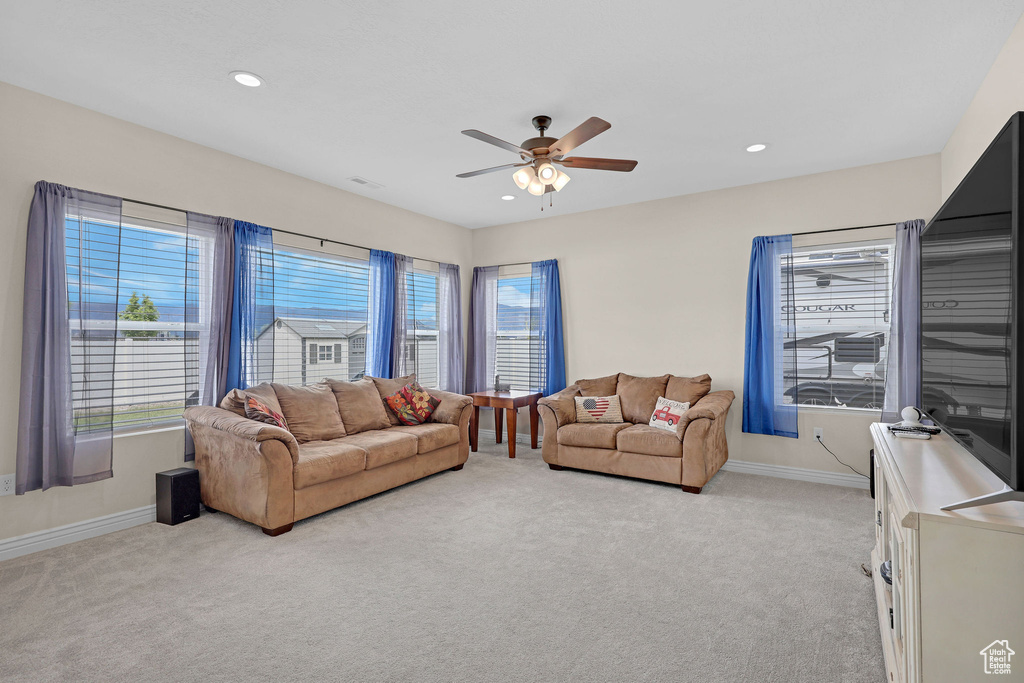 Living room featuring light colored carpet, ceiling fan, baseboards, and recessed lighting