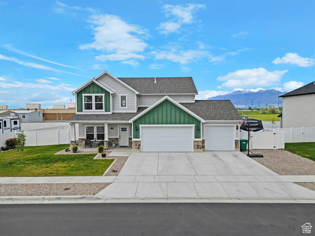 View of front of property featuring board and batten siding, a garage, a mountain view, and stone siding
