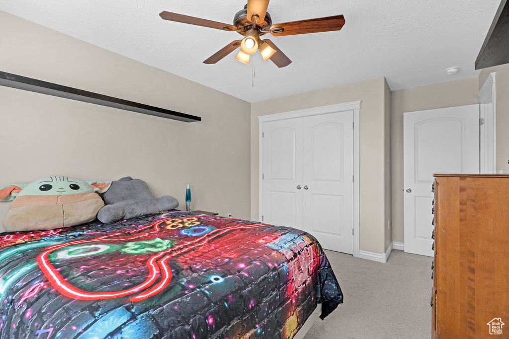 Bedroom with light colored carpet, a closet, ceiling fan, and baseboards
