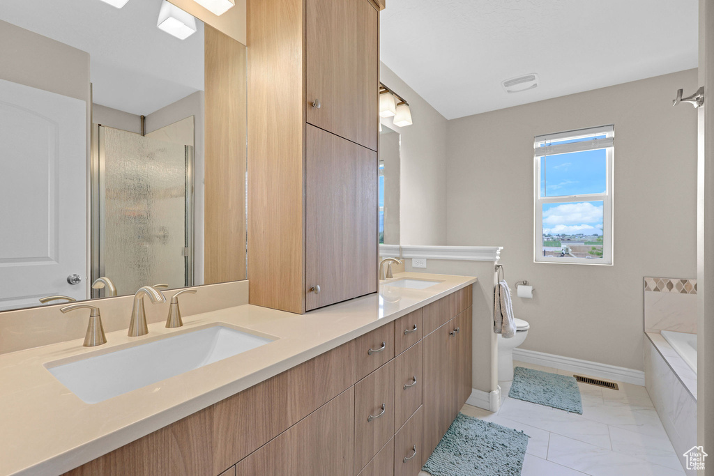 Full bathroom featuring toilet, a stall shower, double vanity, baseboards, and a bath