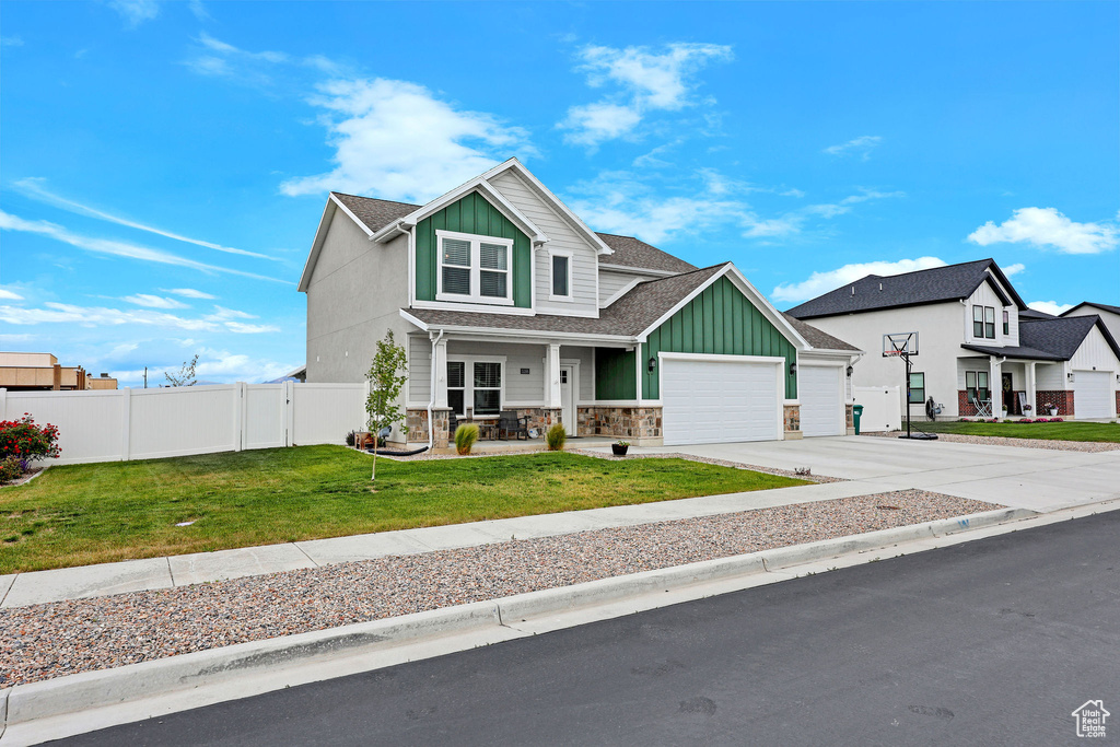 View of front of house featuring board and batten siding, a porch, a garage, driveway, and stone siding