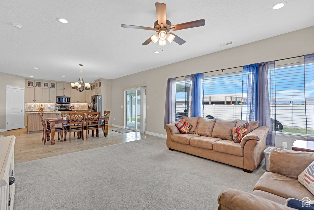 Living area featuring a chandelier, recessed lighting, a ceiling fan, baseboards, and light carpet