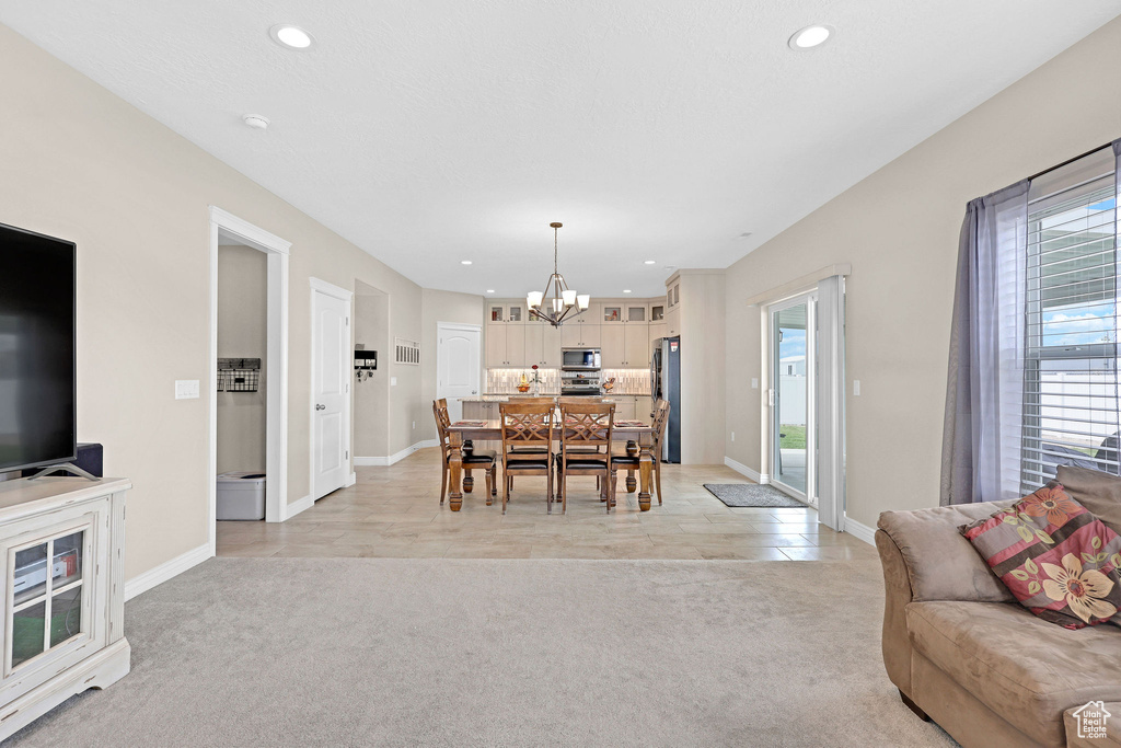 Dining space featuring a chandelier, light carpet, recessed lighting, and baseboards
