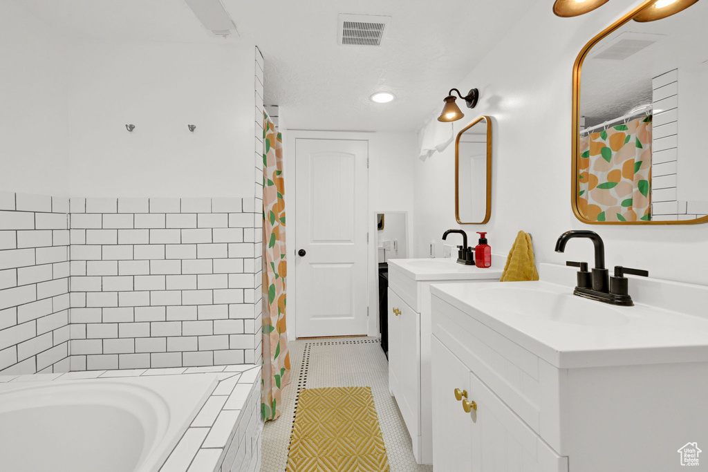 Bathroom with two vanities, tiled bath, a shower with curtain, tile patterned flooring, and recessed lighting