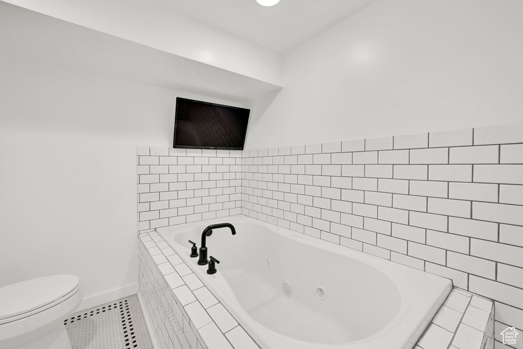Full bathroom with tile patterned floors, a whirlpool tub, toilet, and baseboards