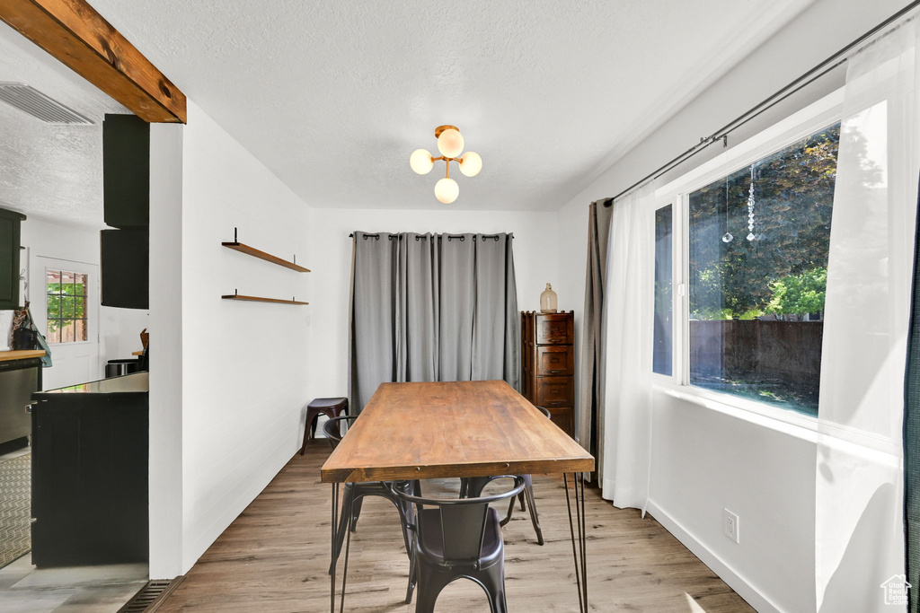 Dining room featuring a textured ceiling, light wood-style floors, and a chandelier