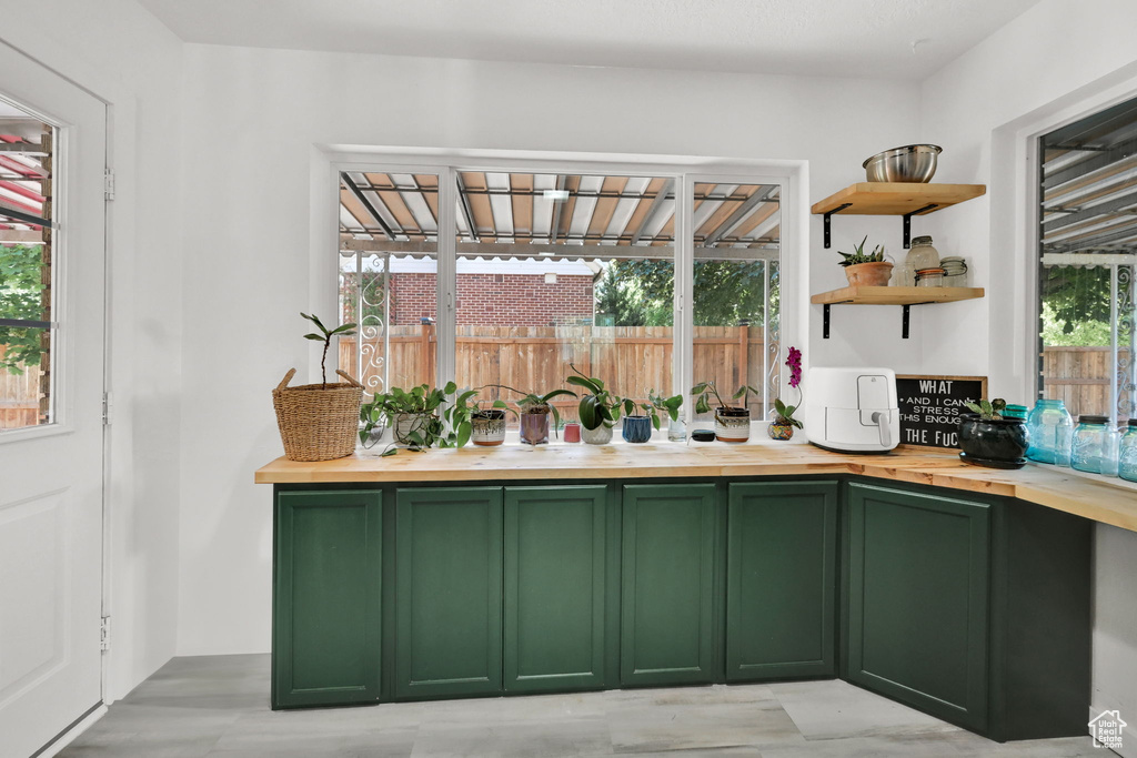 Kitchen with green cabinets, butcher block counters, and open shelves