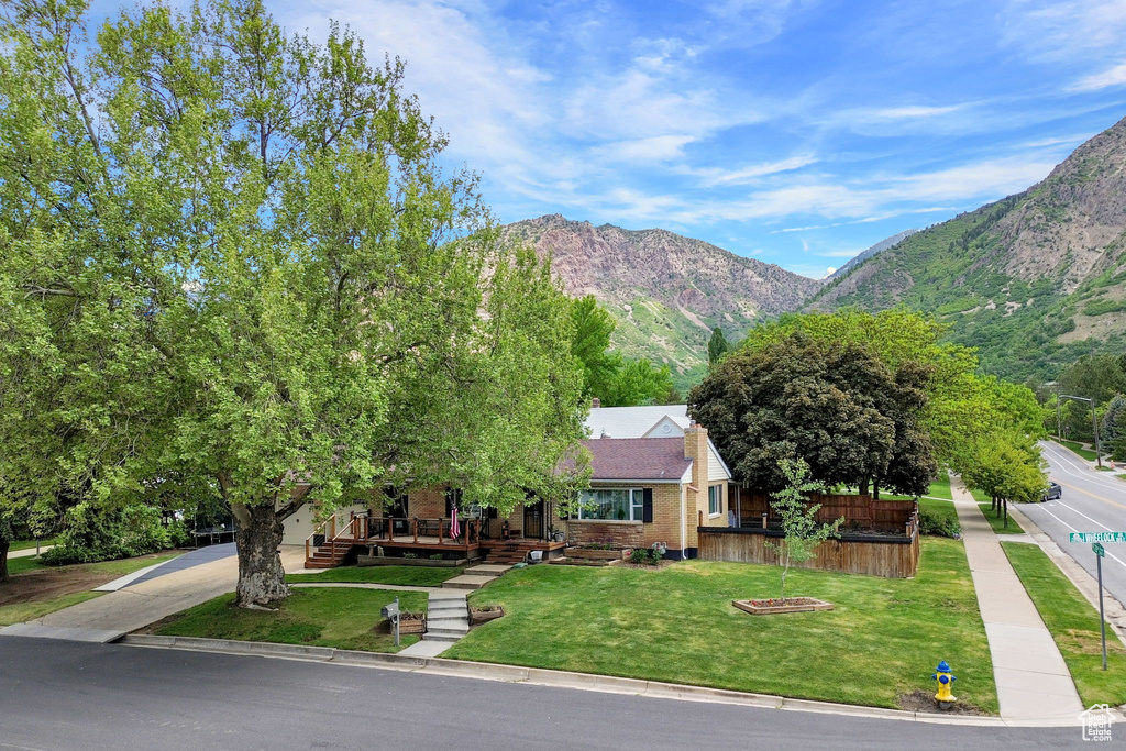 View of front of property featuring a front yard, a mountain view, a porch, and brick siding